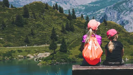 Image d'ambiance de deux fillettes assises sur un ban au bord d'un. la de montagne
