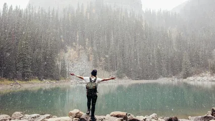Image d'ambiance d’une personne se sentant bien au bord d'un lac de montagne sous la neige